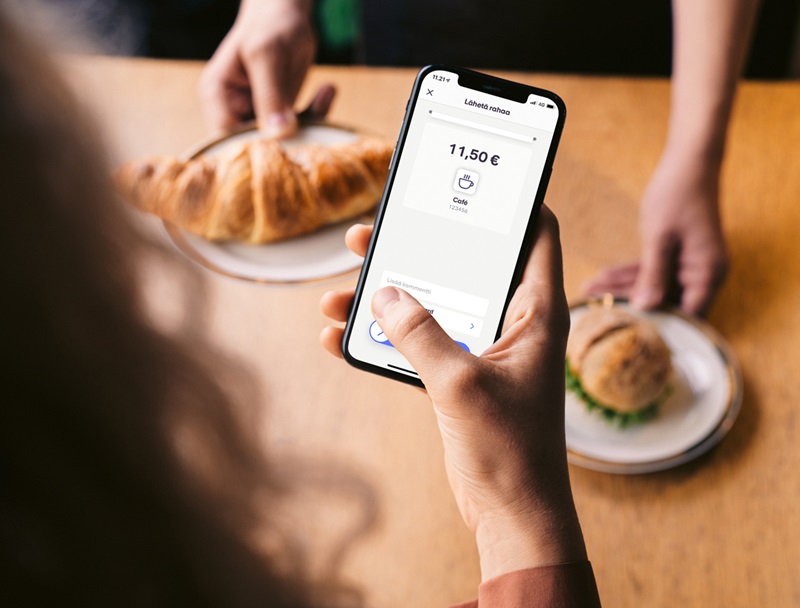 Nainen maksaa välipalan MobilePay sovelluksella kahvilassa