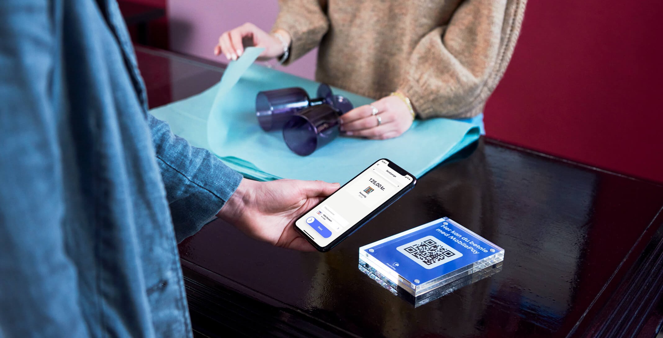 Billede som viser MobilePay-betaling via QR-kode i en interiør butik.